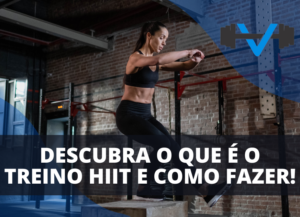 Mulher realizando treino HIIT em academia, pulando sobre uma caixa de madeira. Logotipo azul de academia no canto superior direito.